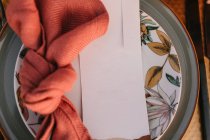Вид зверху декоративної тарілки з барвистою серветкою з вузлом і білою вітальною листівкою, розміщеною на столі під час весільного торжества — стокове фото