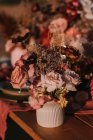 Bunte blühende Rosen mit zarten Blütenblättern in der Vase auf dem Tisch mit Teller und Besteck bei der Hochzeitsfeier auf der Straße — Stockfoto