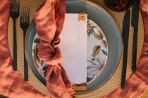 Vista superior da placa ornamental com guardanapo colorido com nó e cartão branco colocado na mesa durante a celebração do casamento — Fotografia de Stock