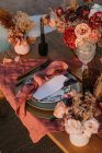 Von oben hölzerne Tischdekoration mit Besteck auf Tellern, serviert auf Tuch neben bunten Blumensträußen mit Weingläsern während der Hochzeitsfeier — Stockfoto