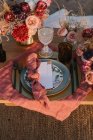 De cima do ajuste de mesa de madeira com talheres em pratos servidos em pano perto de buquês coloridos de flores com vinhedos durante a celebração do casamento — Fotografia de Stock