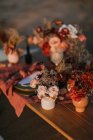 From above of wooden table setting with cutlery on plates served on cloth near colorful bouquets of flowers with wineglasses during wedding celebration — Stock Photo