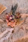 Von oben Anordnung frischer rosa Blumen mit Pflanze und dekorativem Zweig auf weichem Plaid mit Schleife während der Hochzeitsfeier platziert — Stockfoto