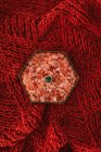 Сверху золотое кольцо с зеленым драгоценным камнем помещается в коробку с розовыми декоративными камнями помещается на красную ткань во время свадебного торжества — стоковое фото