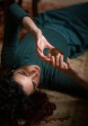 Femme détendue aux cheveux noirs couchée sur un tapis avec boule de cristal transparente dans une chambre au design rétro — Photo de stock