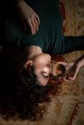 Mulher relaxada com cabelo preto deitado no tapete com bola de cristal transparente no quarto com design retro — Fotografia de Stock