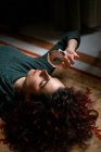 Вид збоку розслабленої жінки з чорним волоссям лежить на килимі з прозорим кришталевим м'ячем в кімнаті з ретро-дизайном — стокове фото