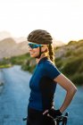 Femme heureuse en vêtements de sport avec casque debout avec vélo sur la nature — Photo de stock