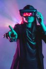 Femme méconnaissable portant un casque VR tout en explorant la réalité virtuelle sous la lumière bleue néon — Photo de stock