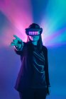 Unrecognizable female with outstretched arm wearing VR headset while exploring virtual reality under blue neon light — Stock Photo
