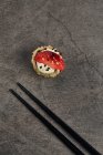 Високий кут смаженого ролу японського суші з кунзамом і полуничним шматочком біля бамбукових паличок. — стокове фото