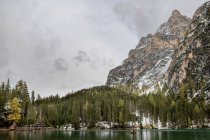Pintoresco paisaje del lago Lago di Braies rodeado de bosques siempreverdes y montañas cubiertas de nieve - foto de stock