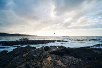 Cenário pitoresco de litoral íngreme rochoso coberto com lavagem de grama por ondas salpicantes — Fotografia de Stock