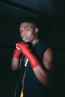 Junger starker afroamerikanischer Sportler in Boxhandschuhen beim Training und beim Blick in die Kamera im Gebäude — Stockfoto