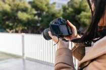 Обрізана невпізнавана жінка-фотограф, що знімає фотографію на професійній фотокамері на міській вулиці — стокове фото