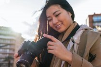 Etnia jovem feliz asiática fotógrafa atirando foto na câmera de fotos profissional na rua da cidade — Fotografia de Stock