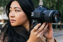Этнические азиатские женщины-фотографы снимают фото на профессиональную фотокамеру на городской улице — стоковое фото