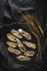 Зверху апетитний грубий хліб біля пшеничних шипів і темної тканини на столі — стокове фото