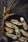 From above of appetizing crusty bread near wheat spikes and dark fabric on table — Stock Photo