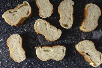 Вид зверху на шматки білого хліба біля ножа та шипів пшениці на дерев'яній дошці — стокове фото
