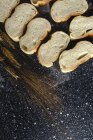 Vue du dessus des morceaux de pain blanc près du couteau et des pointes de blé sur une planche de bois — Photo de stock