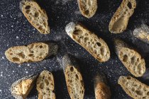 Dall'alto di pane croccante appetitoso vicino a spuntoni di grano e tessuto scuro sul tavolo — Foto stock