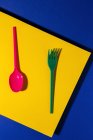 Overhead view of bright colorful eco friendly cutlery near yellow carton sheet — Stock Photo