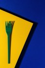 Overhead view of bright green eco friendly fork near yellow carton sheet on blue background — Stock Photo