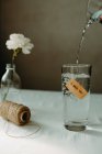 Water pouring into glassware with inscription i miss you placed near skein of thread and blooming carnation — Stock Photo