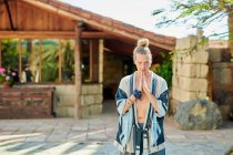Junger Mann mit Namaste-Händen blickt im Sommer beim Yoga gegen Altbau in die Kamera — Stockfoto