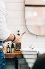 Crop unrecognizable male stylist holding straight razor with sharp blade in beauty salon in daytime — Fotografia de Stock