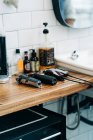 Sammlung von professionellen elektrischen Haarschneidemaschinen in der Nähe von Flaschen mit Kosmetikprodukten und Waschbecken im Badezimmer des Friseursalons — Stockfoto