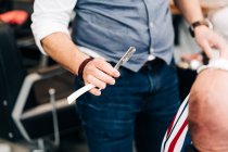 Ernte unkenntlich männlichen Stylisten hält Rasiermesser mit scharfer Klinge in Schönheitssalon tagsüber — Stockfoto