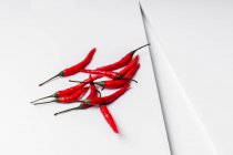 High angle composition of hot red chili peppers arranged plate against white geometric surface background — Stock Photo