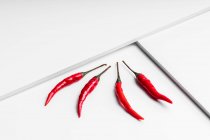 High angle composition of hot red chili peppers arranged plate against white geometric surface background — Stock Photo