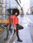 Füllen Sie die Körperseite einer selbstbewussten Afroamerikanerin mit Afro-Frisur, die auf dem Bürgersteig steht und wegschaut — Stockfoto