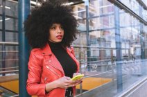 Riempi la vista laterale del corpo di donna afro-americana fiduciosa con acconciatura Afro in piedi sul marciapiede e distogliendo lo sguardo — Foto stock