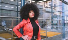 Fill body side view of confident African American female with Afro hairstyle standing on sidewalk and looking away — Stock Photo