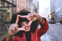 Entzückte junge Afroamerikanerin demonstriert Geste, während sie strahlend lächelt und in die Kamera blickt — Stockfoto