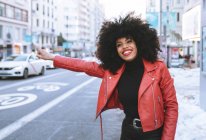 Pieno corpo di positivo giovane donna afroamericana indossa vestito alla moda in piedi su strada innevata e prendere un taxi — Foto stock