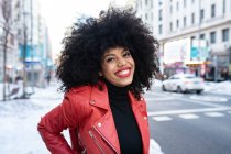 Чорна жінка з афро волоссям на вулиці і посміхається на камеру — стокове фото