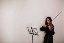 Artiste sérieux jouant de l'instrument de musique à cordes tout en pratiquant des compétences debout sur fond blanc — Photo de stock