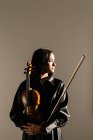 Violinista femenina de pie con instrumento musical y ojos bien cerrados - foto de stock