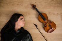 Mulher e violino acústico moderno e arco de design clássico colocado na superfície de madeira em estúdio musical — Fotografia de Stock