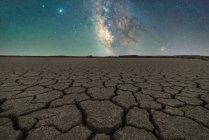 Drought cracked lifeless ground arid terrain with starry sky at night — Stock Photo