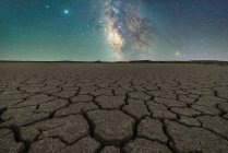 Sécheresse terrain aride, sans vie, fissuré, avec ciel étoilé la nuit — Photo de stock