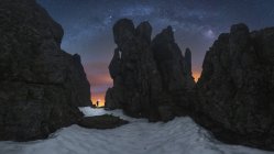 Силует анонімного дослідника з ліхтариком, що стоїть між скелястими скелями і захоплюючим темним зоряним небом у національному парку Пікос - де - Європа. — стокове фото