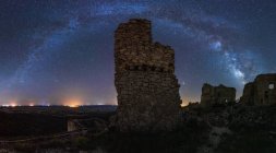 De baixo da paisagem pitoresca do castelo arruinado antigo no prado abaixo da Via Láctea no céu estrelado à noite — Fotografia de Stock