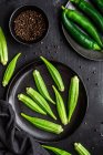 Vista dall'alto di superfood verde maturo su piatti neri di ceramica vicino a pepe in boccia su tavolo — Foto stock