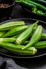 Vista dall'alto di superfood verde maturo su piatti neri di ceramica vicino a pepe in boccia su tavolo — Foto stock